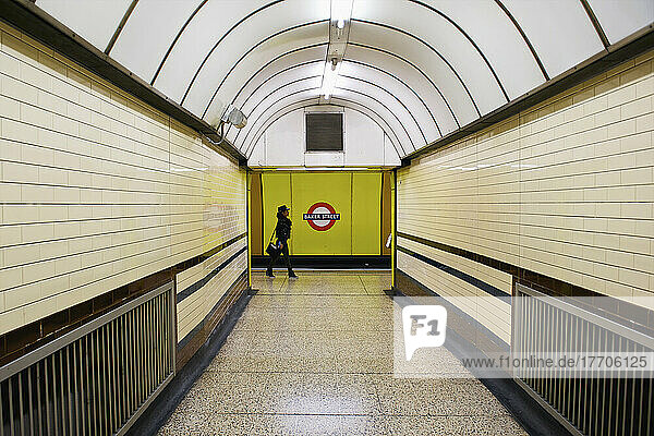 Eine Frau geht am Ende eines Korridors mit gewölbter Decke in der Londoner U-Bahn; London  England