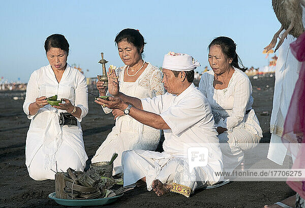 Familie und Priester machen eine Opfergabe beim Melasti-Festival zu Ehren der Meeresgötter; Bali  Indonesien