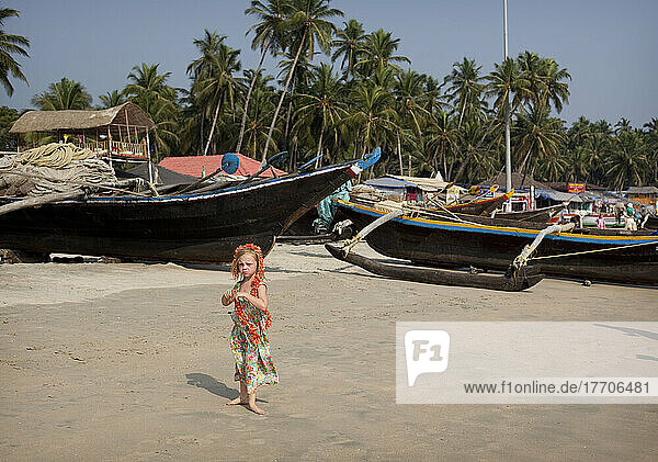 Isla Reynolds  4 Jahre alt  steht vor den vielen traditionellen Booten und Strandrestaurants  die den Strand von Palolem  Goa  Indien  säumen.