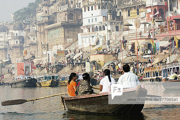 Indische Familie  die den heiligen  aber verschmutzten Fluss Ganges entlang rudert  vorbei an badenden Ghats; Uttar Pradesh  Indien