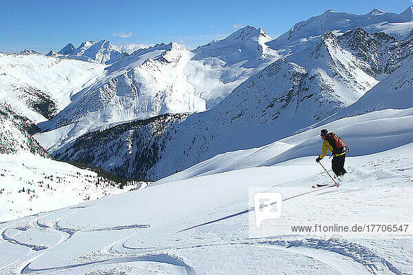 A lone backcountry skiier heads downhill in the Selkirk Mountains; British Columbia  Canada