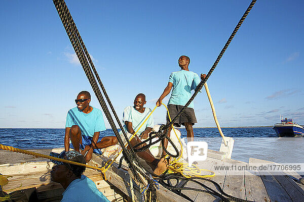 Drei Männer arbeiten gemeinsam an einem Segelboot; Insel Vamizi  Mosambik