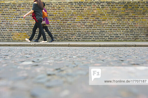 Junge Frauen gehen neben einem Backsteingebäude entlang der Portobello Road; London  England
