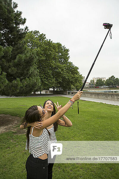 At the Parc de la Villette  two girls use a pole to take a self-portrait in Paris  France; Paris  France