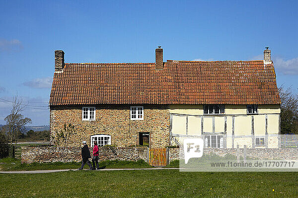 Ein Paar spaziert an einem Haus mit zwei verschiedenen Fassaden vorbei; Frampton Upon Severn  Gloucestershire  England