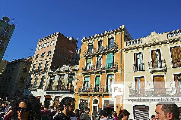 Fußgänger gehen auf einer Straße mit Wohngebäuden und blauem Himmel; Barcelona  Spanien