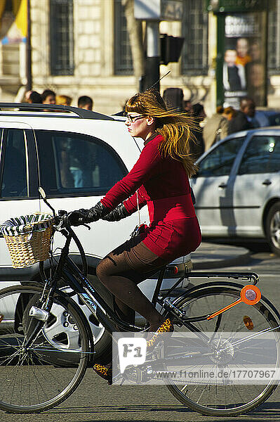 Eine Frau in formeller Geschäftskleidung fährt mit dem Fahrrad im Verkehr; Paris  Frankreich
