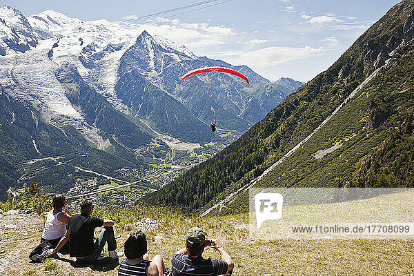 Touristen  die einen Gleitschirmflug am Startplatz über dem Chamonix-Mont-Blanc-Tal beobachten  mit dem Mont Blanc im Hintergrund; Frankreich
