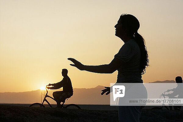 Silhouette Of Cyclists And A Woman Doing Yoga At Sunrise; California  United States Of America