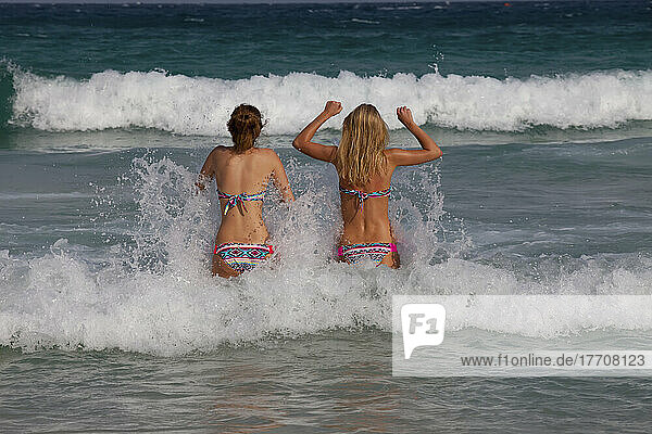 Mädchen in passenden Bikinis gehen ins Meer.