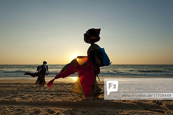Silhouette einer Frau  die am Strand in der Abenddämmerung indische Tücher verkauft; Candolim  Goa  Indien