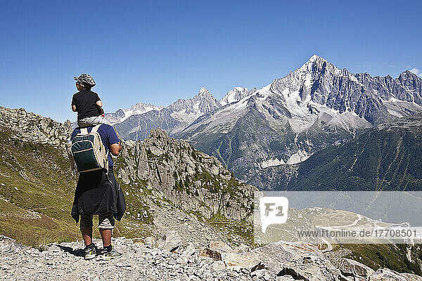 Hikers Above Chamonix-Mont Blanc Valley  With Mont Blanc Massif Range Mountain In The Background; France