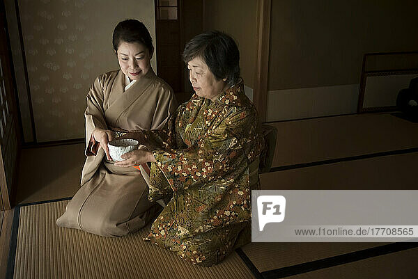 Zwei Frauen nehmen an einer traditionellen japanischen Teezeremonie auf der Insel Miyajima teil. Die japanische Teezeremonie oder Chado ist eine kulturelle Aktivität  die die zeremonielle Zubereitung und Darbietung von pulverisiertem grünem Tee beinhaltet. Es kann sich dabei um informelle Zusammenkünfte oder sehr formelle Zeremonien handeln. Chado gilt als eine der drei klassischen japanischen Künste der Verfeinerung  zusammen mit Kodo für die Wertschätzung von Räucherstäbchen und Kado für Blumenarrangements; Miyajima  Japan