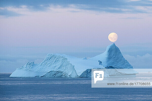 Full moon sets over an iceberg in the Gerlache Strait off the coast of the Antarctic peninsula; Antarctica