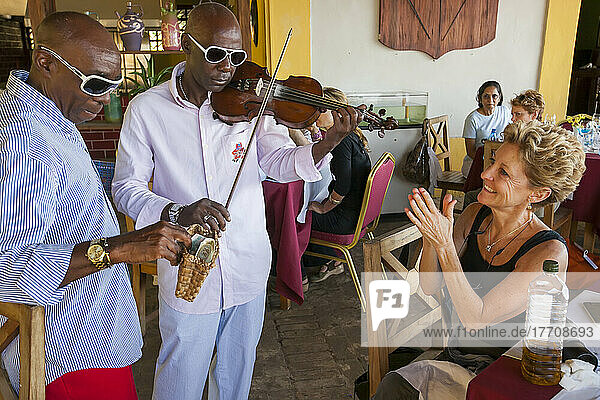 Ein Tourist in einem Restaurant in Havanna  Kuba  applaudiert zu einer Geigenmusik  während ein Mann Geld für die Unterhaltung sammelt; Havanna  Kuba