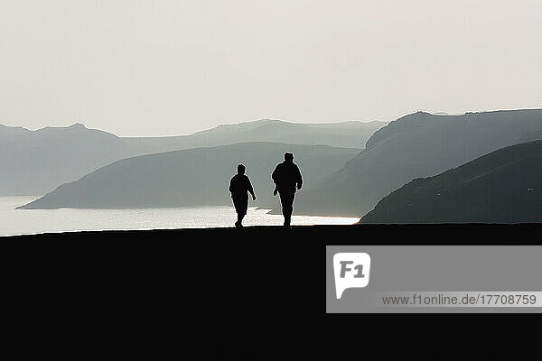 Zwei Wanderer in der Nähe von Martin's Haven bei Sonnenuntergang auf dem Pembrokeshire Coast Path; Wales