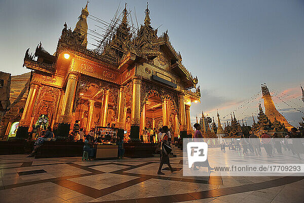 Besucher spazieren um die Shwedagon-Pagode bei Sonnenuntergang; Yangon  Burma