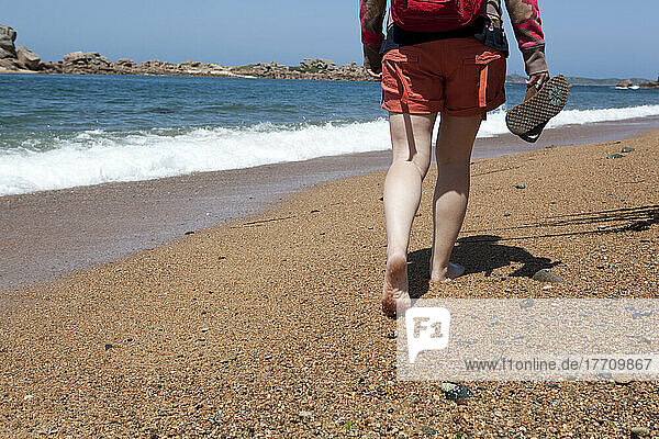 Junge Frau spaziert am Strand in der nördlichen Bretagne  Frankreich