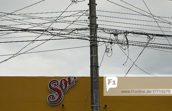 Elektrische Drähte und Telefonkabel mit einem Schild an einer gelben Wand; Tulum  Mexiko