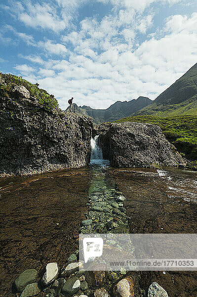 Mann betrachtet kleinen Wasserfall in der Nähe der Fairy Pools in Coire Na Creiche  Black Cuillin; Isle Of Skye  Schottland