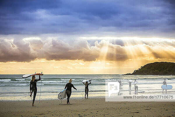 Ein wunderschöner Sonnenaufgang begrüßt die Surfer  die sich auf das morgendliche Surfen vorbereiten und hinauspaddeln; Arrawarra  New South Wales  Australien
