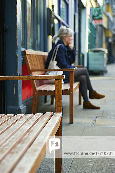 Eine Frau sitzt auf einer Bank vor einem Gebäude  Shoreditch; London  England