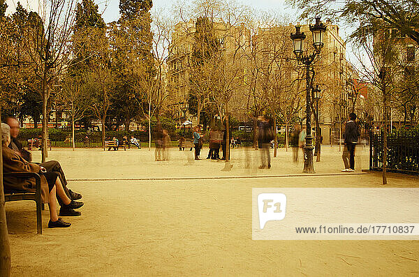 Langzeitbelichtung von Menschen  die in der Nähe der Sagrada Familia durch einen Park mit Sepiatönung schlendern; Barcelona  Spanien