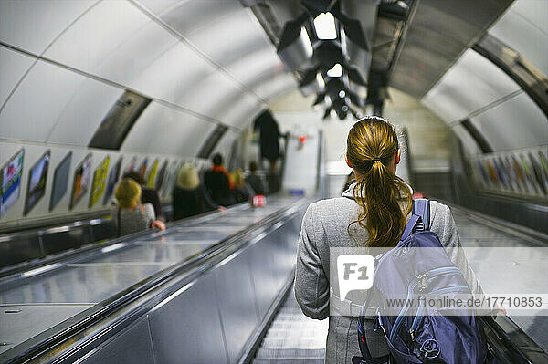 Junge Frau auf Rolltreppe in Londoner U-Bahn; London  England