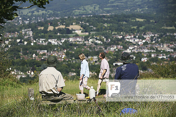 Wanderer bei einer Picknick-Mittagsrast und andere Wanderer auf dem berühmten nationalen Wanderweg 100-Meilen-Weg des Cotswold Way oberhalb von Cheltenham; Gloucestershire  England