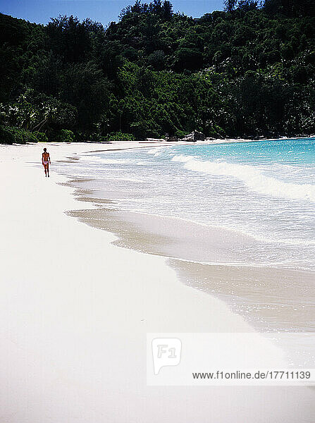 Frau geht an einem tropischen Strand spazieren