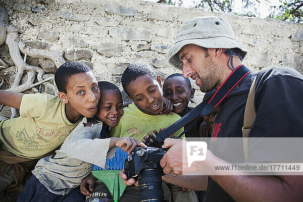 Tourist  der Kindern Bilder auf der Rückseite der Kamera zeigt; Äthiopien