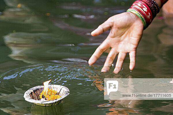 Hinduistische Frau  die in das heilige Wasser des Ganges eintaucht und ein Gefäß mit einer Flamme als religiöses Opfer abwirft; Bundesstaat Uttar Pradesh  Indien