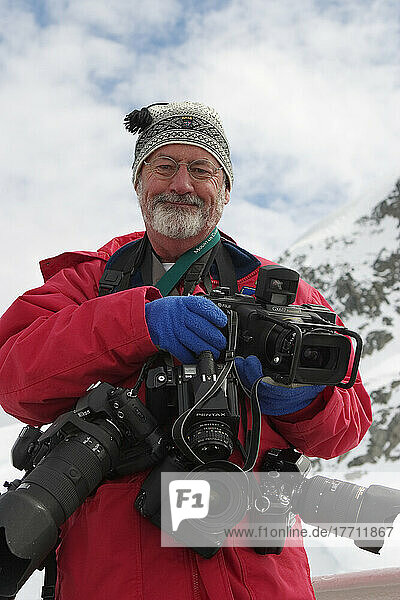 Portrait of a photographer and his equipment in winter clothing.