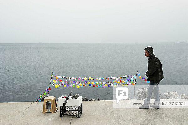 A Young Man Sets Up A Shooting Target At The Water's Edge; Istanbul  Turkey