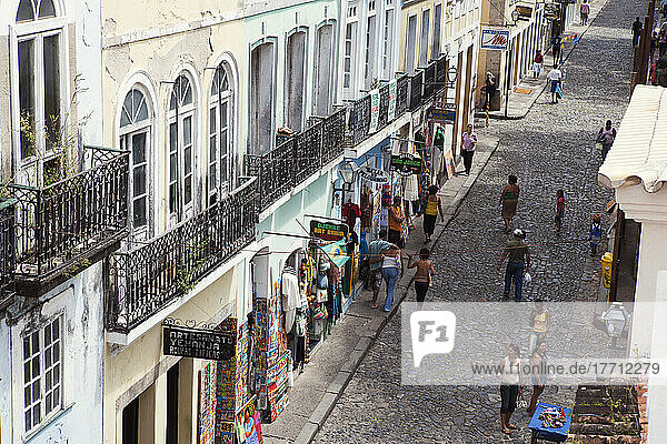 Cobbled Shopping Street In The Historical Centre Of The Old Colonial City  With Paintings And Clothes On Display And Shoppers Strolling Past; Salvador  Brazil