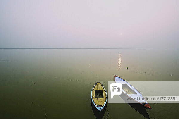 Zwei Holzboote sitzen auf dem ruhigen Wasser des Ganges; Varanasi  Indien