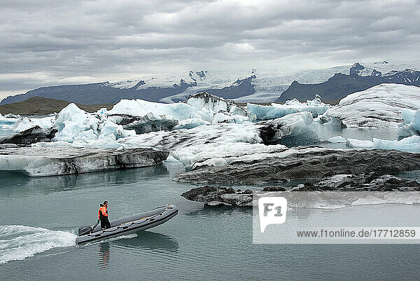 Tourist auf einem Schlauchboot in der Gletscherflusslagune  wo gekalkte Eisberge vom Vatnajokull-Gletscher in die Lagune fallen und dort bleiben  bis sie klein genug sind  um ins Meer zu gelangen. Der Vatnajokull ist der größte Gletscher Islands auf dem Skalafellsjokull-Finger des Gletschers  Vatnajokull-Nationalpark; Island