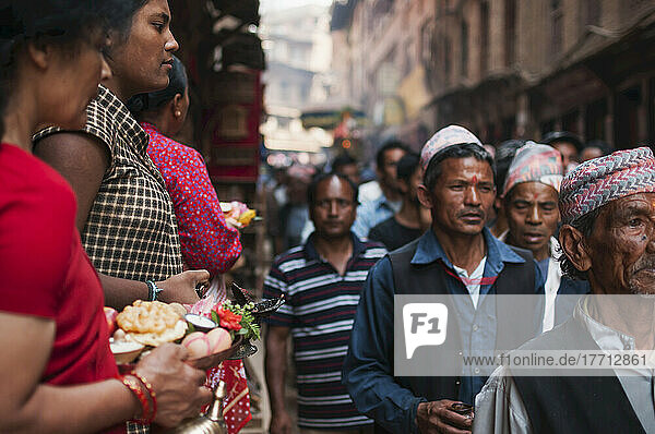 Nepalesisches Neujahrsfest mit Menschen  die eine buddhistische Gottheit tragen und Frauen  die ihr Opfergaben darbringen; Bahktapur  Kathmandutal  Nepal