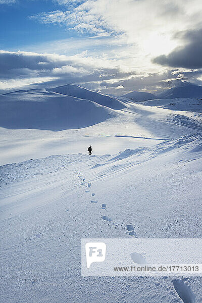 Wanderer auf einem verschneiten Winterspaziergang beim Abstieg vom Creag Pitridh  in der Nähe von Laggan; Schottland