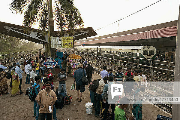 Fahrgäste warten auf dem Bahnsteig eines Bahnhofs auf ankommende Züge; Indien