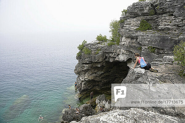 Junge Frau schaut über die Klippe zu den Schwimmern unten im Bruce Peninsula National Park; Ontario  Kanada