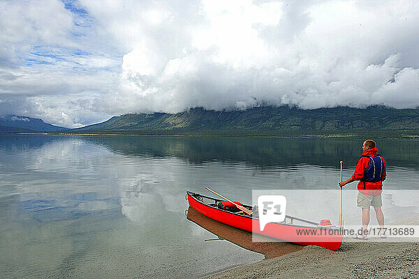 Man Standing Beside A Canoe Holding A Paddle  Kusawa Lake  Yukon