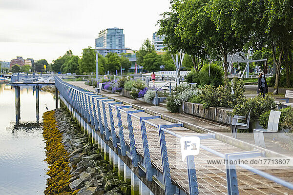 Drahtzaun und Promenade neben dem Hafen mit Menschen  die während der Covid-19-Pandemie durch den Stadtpark spazieren; Vancouver  British Columbia  Kanada