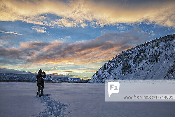Fotograf beim Fotografieren des Sonnenuntergangs über dem Yukon River; Dawson City  Yukon  Kanada