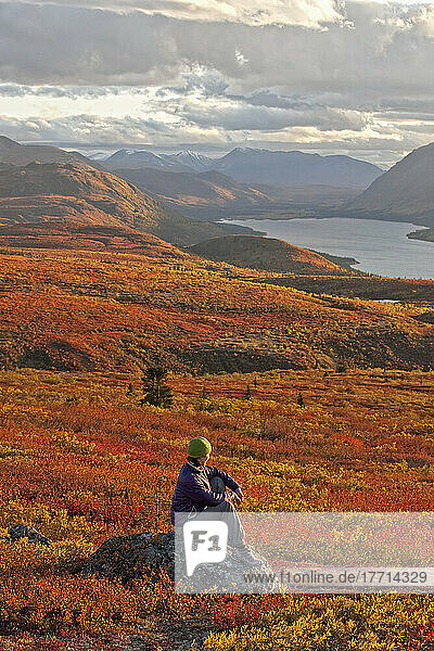 Frau sitzt auf einem Felsen in der Nähe des Fischsees; Whitehorse Yukon Kanada