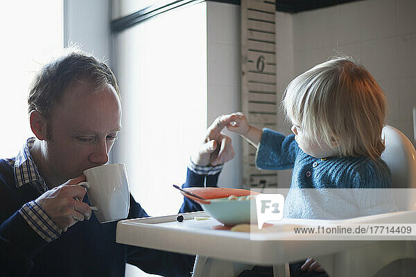 Toddler And Uncle Having Cereal For Breakfast In The Kitchen; Toronto  Ontario  Canada