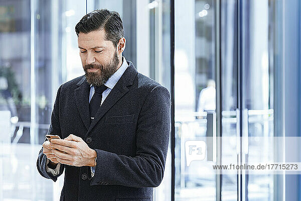 Businessman wearing suit looking at cell phone outdoors; Toronto  Ontario  Canada