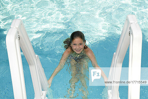 Junges Mädchen klettert auf eine Schwimmbadleiter; Ontario Kanada