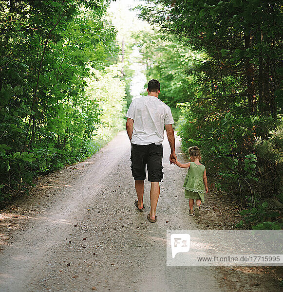 Vater und Tochter wandern auf der Landstraße