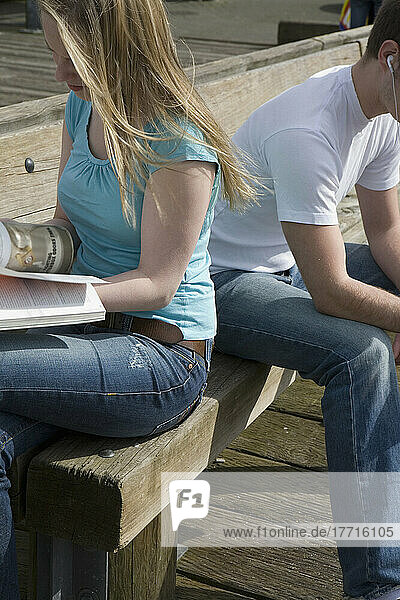 Paar  das auf einer Bank auf einem Dock sitzt und liest  Granville Island  Vancouver  British Columbia